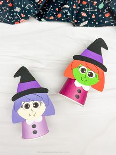 two paper cups with witches on them sitting on a bed next to another cup that has been cut out