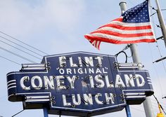 an old sign that says flint original coney island lunch with the american flag flying in the background