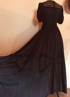 "This beautifully made 1930s silky rayon dress is rich with detail and workmanship.  It has full puffed sleeves, gathered around the bicep, and across the front and back yoke it has a silk tulle with slim strips of the rayon body fabric, creating a partially see-through area.  The dress undoes via a long row of covered buttons down the centre back. The skirted section of the dress is full length and very full, with appliquéd large bows around the hemline, made from the tightly ruched silky rayon fabric. ------------------------------------------------ Measurements: Bust at underarm: 34\" Waist: 28\" Hips: free Length from centre front neck to hem: 55½\" Condition: generally excellent, with some 'grinning' to the vertical seams on the waist and bust. ---------------------------------------- Vintage Satin Victorian Costume Dress, Vintage Victorian Satin Costume Dress, Vintage Victorian Satin Dress For Costume, Vintage Satin Victorian Dress For Costume, Regency Style Black Evening Dress, Black Regency Style Evening Dress, Vintage Victorian Satin Dress For Formal Occasions, Vintage Satin Victorian Dress For Formal Occasions, Formal Vintage Victorian Satin Dress