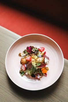 a white plate topped with lots of food on top of a wooden table next to a red wall