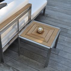 a coffee table and couch on a wooden deck with white sheets in the back ground