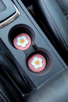 two cupcakes in the middle of a car's center console with flowers on them