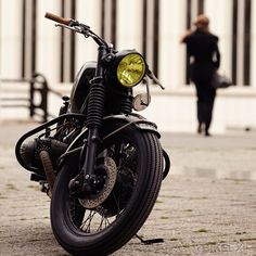 a black motorcycle parked on the side of a street next to a tall white building