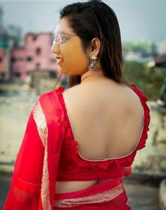 a woman in a red sari looking off to the side with her back turned