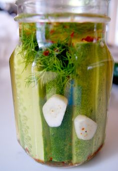 a jar filled with cucumbers and herbs