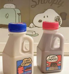 two jugs of coffee sitting next to each other on a counter with snoopy wallpaper