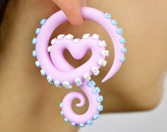 a close up of a person wearing large pink ear rings with heart shaped beads on them