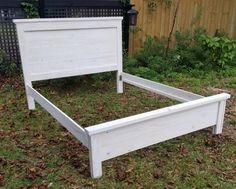 a white bed frame sitting in the grass