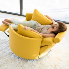 a woman laying on top of a yellow chair in a living room next to a window