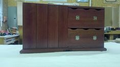 a large wooden cabinet sitting on top of a white bed in a room filled with furniture