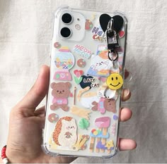 someone is holding up their phone case with many stickers on it and there are two keys attached to the back