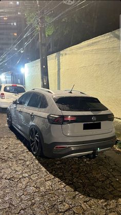 two cars parked on the side of a road next to a wall and street lights