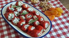 a plate full of stuffed tomatoes and cheese on a checkered tablecloth with nuts