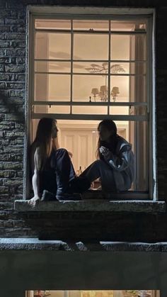 two people sitting on a window sill looking at each other