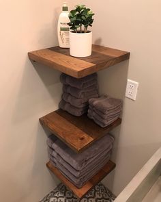 a stack of folded towels sitting on top of a wooden shelf next to a potted plant