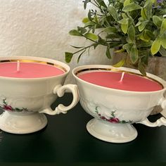 two tea cups with candles in them on a table