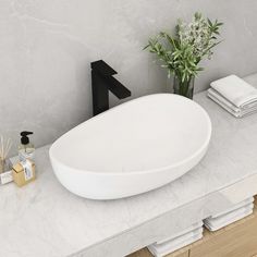 a white sink sitting on top of a counter next to a vase with flowers in it