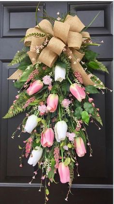 a wreath hanging on the front door of a house with pink and white flowers in it