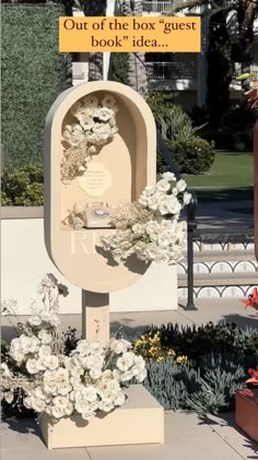 a sign that says out of the box guest book idea with flowers in front of it