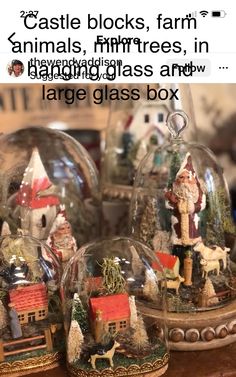 some glass houses are sitting on top of a table with santa clause figurines in them