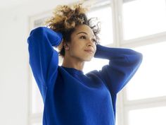 a woman wearing a blue sweater is posing for the camera with her hands on her head