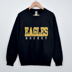 a black sweatshirt with the words eagles hockey on it hanging on a wooden hanger