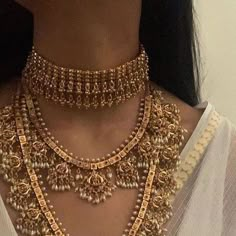 a close up of a woman wearing a gold necklace and bracelet with pearls on it