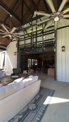 an open living room with white couches and ceiling fan in the middle of it