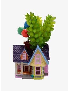 a small toy house with balloons on the roof and trees growing out of it's roof