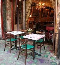 tables and chairs in front of a restaurant with an open door to the outside area