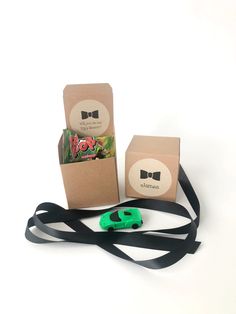 a green pair of scissors sitting on top of a black ribbon next to a brown box