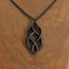 a wooden necklace with an intricate design hanging from it's chain on a wood surface