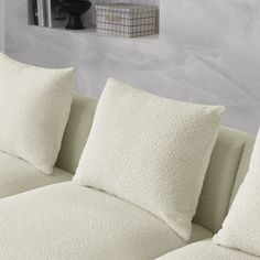 a white couch with pillows on it in front of a book shelf and bookshelf