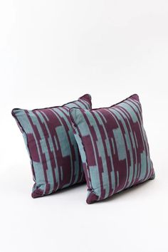 two purple and blue pillows sitting on top of each other