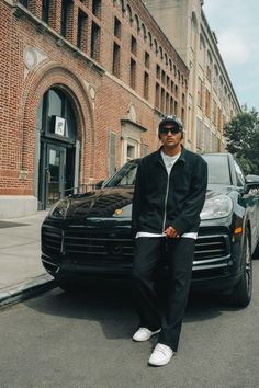 a man standing in front of a black car