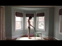 a woman standing in front of a window with a mop on the floor next to her