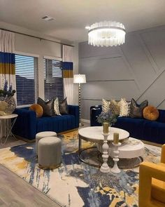 a living room with blue couches, yellow chairs and a chandelier hanging from the ceiling