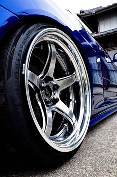 a blue car with chrome rims parked in front of a building