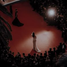 a woman standing on top of a red carpet in front of a group of people