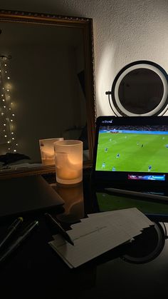 a laptop computer sitting on top of a desk next to a mirror and lit candle