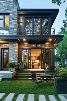 a modern house with stairs leading up to the front door and an outdoor seating area