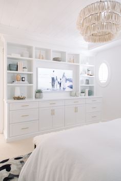 a bedroom with white furniture and a chandelier hanging from the ceiling above it