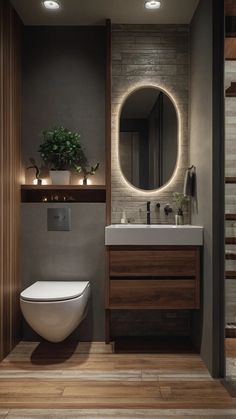 a bathroom with a toilet, sink and mirror on the wall next to wooden flooring