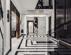 an elegant hallway with black and white marble flooring, chandelier and art deco door