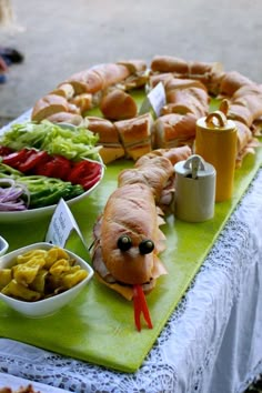 a table topped with lots of food on top of a green cloth covered tablecloth