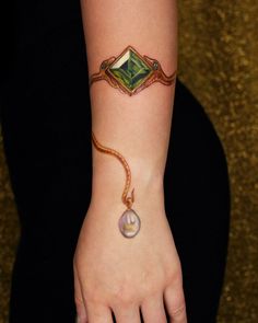 a woman's hand with a green and white bracelet on her left wrist that has a ring around it