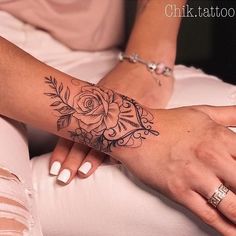 a woman's arm with a rose tattoo on it, sitting next to her legs