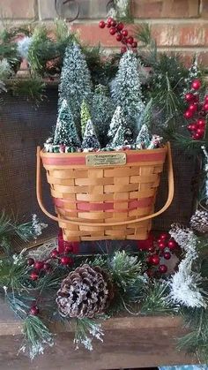 a basket filled with christmas trees sitting on top of a wooden table next to pine cones