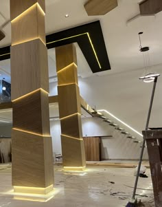 an unfinished room with wooden columns and lights on the ceiling, in front of a staircase