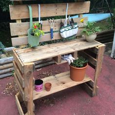 a wooden bench with potted plants and gardening utensils hanging on the back